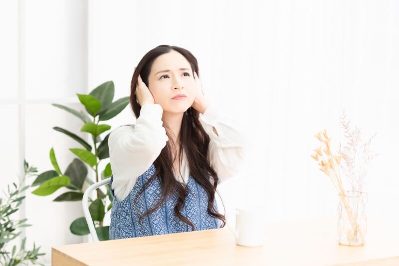 耳をふさぐ女性